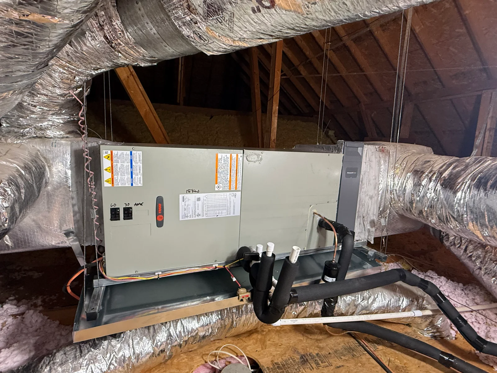 Trane attic air handler with insulated flex ducts, foam-wrapped refrigerant lines, and PVC condensate piping