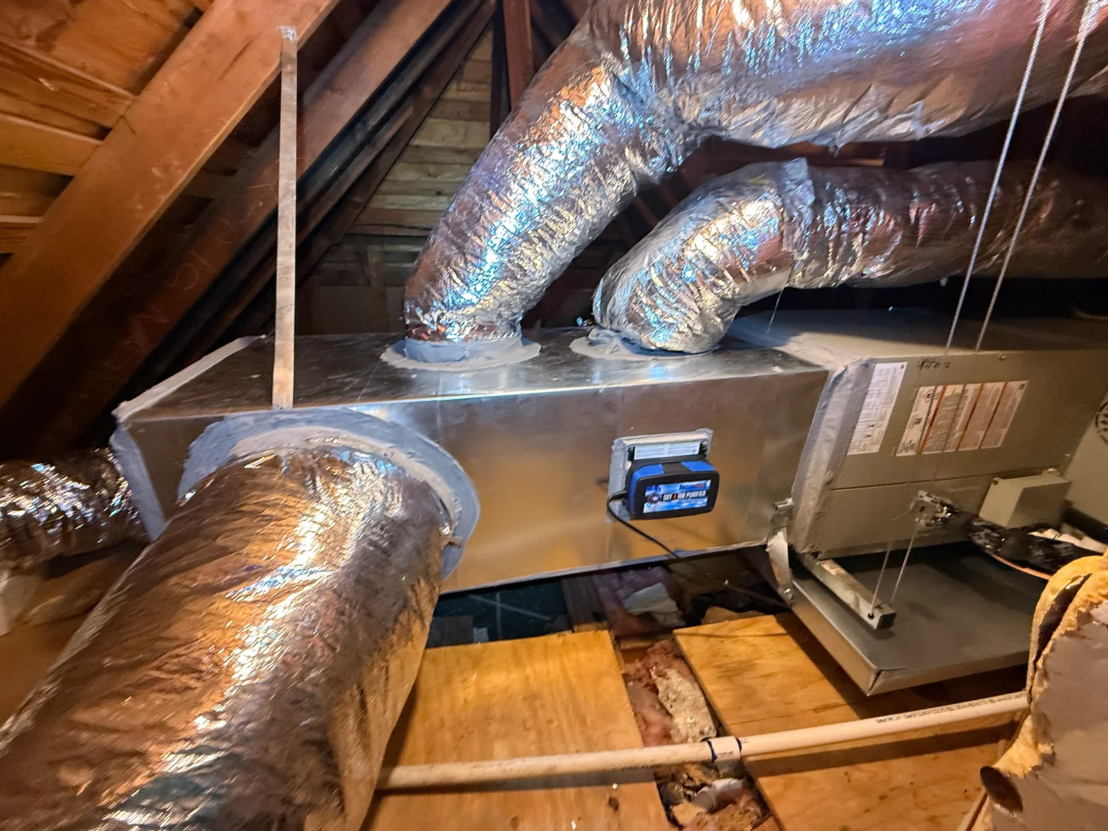 Attic furnace with galvanized plenum, insulated flex ducts, and mounted air purifier on wood platform